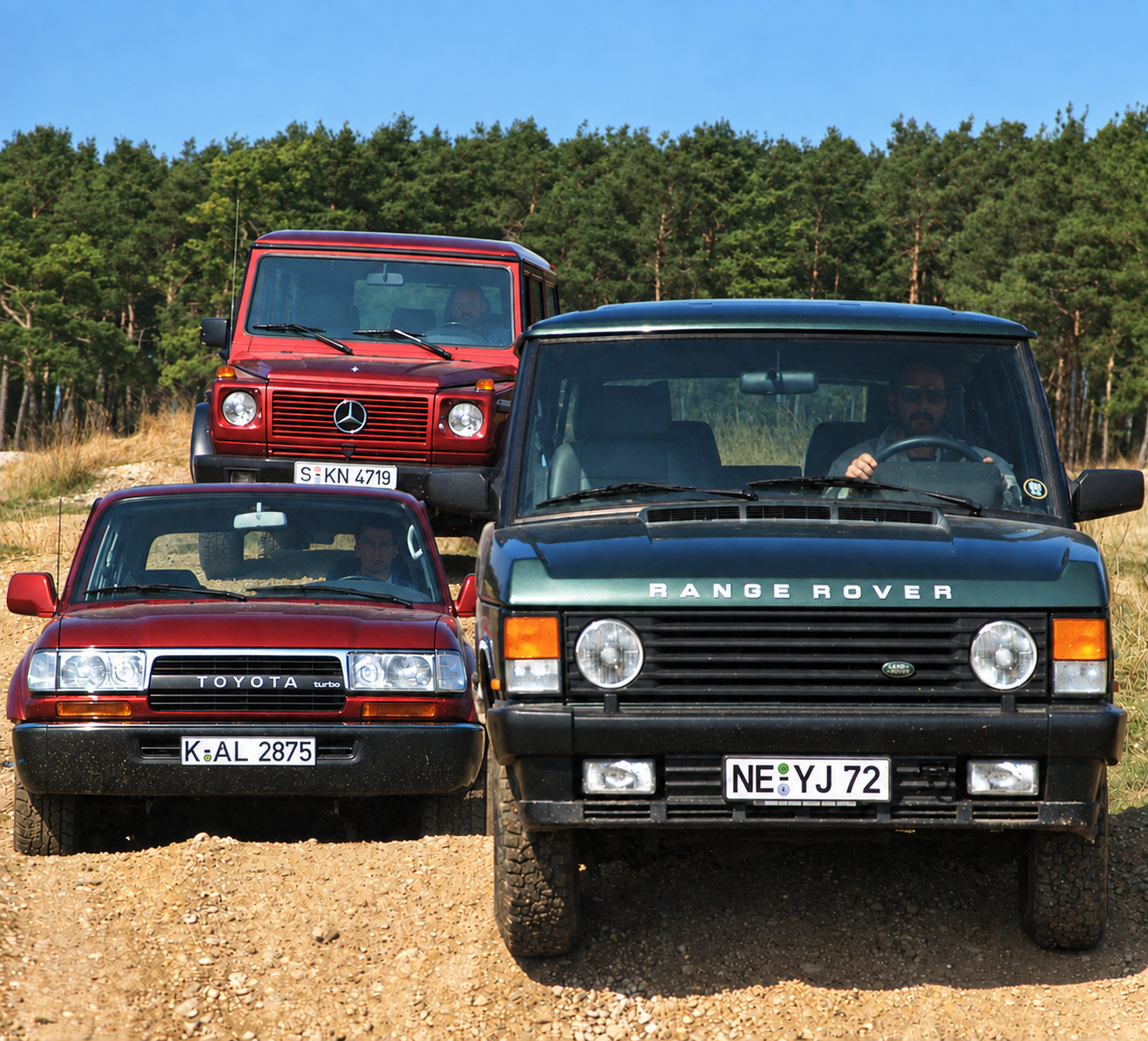 Fotografia originale del 1991: Mercedes 300 GE rossa, Toyota HDJ 80 rossa e Range Rover verde schierate sullo sterrato — restauro assistito da IA dalla scansione originale